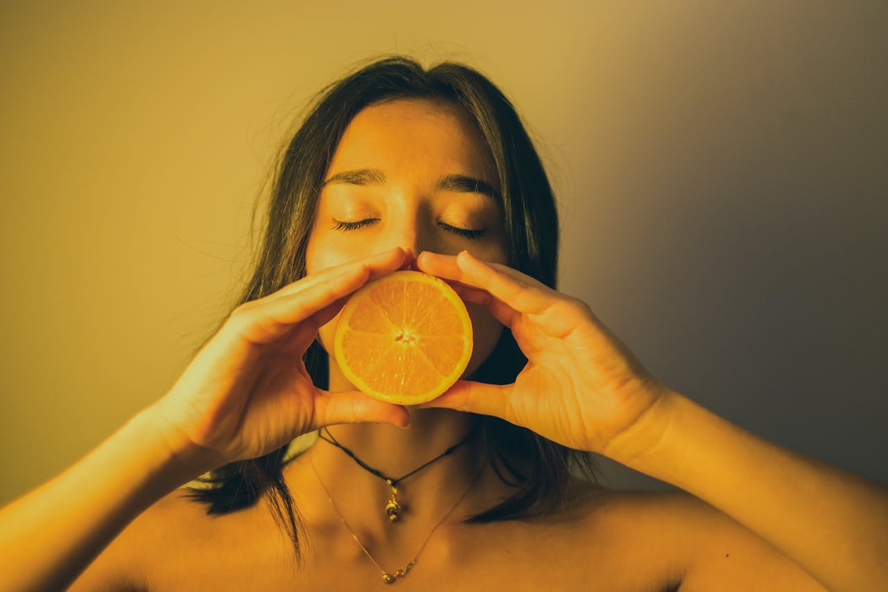 ttractive-woman-with-eyes-closed-holding- sweet orange-slice-against-lips-